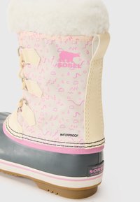 Wasserfeste Sorel-Stiefel mit beigem Stoff-Obermaterial, das pinke abstrakte Muster zeigt, grauer Gummisohle, weißem Fellkragen und Schnürhardware.