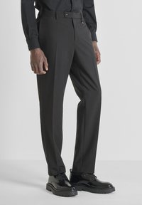 Pantalones de vestir negros con un corte entallado, que presentan una textura suave, piernas rectas, presillas para cinturón y bolsillos delanteros. Combinados con zapatos negros.