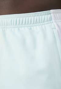 Pantalones cortos deportivos de color azul claro con una cinturilla elástica, que presentan una tela texturizada y acentos blancos en los laterales. Enfoque en la comodidad y la movilidad.