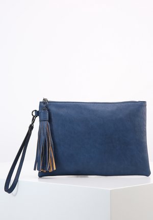 Blaue Leder-Clutch mit Handgelenksriemen und Quasten-Detail, auf einem weißen Podest vor hellem Hintergrund präsentiert.