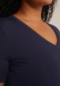 Camiseta de cuello en V azul marino, hecha de una suave mezcla de algodón, con mangas cortas y un corte ajustado, realzada por costuras limpias.