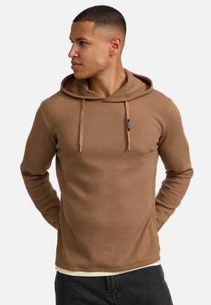 Bruine geribde hoodie met een trekkoord, featuring een logo patch en gestructureerde stof. Slim fit, lange mouwen en gelaagde look aan de onderkant.