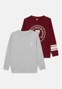 Due felpe a manica lunga: una grigia con un logo rotondo e una bordeaux con strisce crema e un logo circolare. Entrambe sono fatte di un tessuto morbido.
