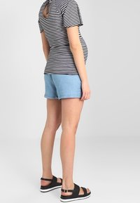 Striped black and white top with a keyhole back, light blue denim shorts, and black sandals with a metallic accent and white sole.
