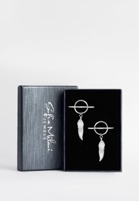 Silverfjäderörhängen med en cirkulär accent, visade i en mörk sammetklädd låda med en texturerad silverutsida.