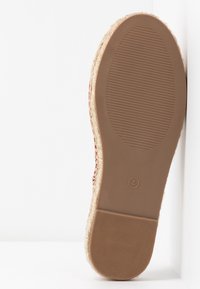 Semelle d'une chaussure taille 4 avec talon et bouts en caoutchouc texturé, détail de bord tissé naturel le long des côtés.