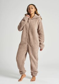 Fleece heldragt i lys beige, med hætte, lynlås lukning og løs pasform. Struktureret, blødt stof med elastiske manchetter og ankler.