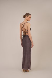 Vedere din spate a unui model îmbrăcat într-o rochie lungă, burgundy, ajustată, cu un finisaj texturat, având un design cu bretele încrucișate și legată la spate.