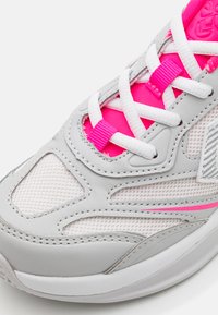 Grå sportskor med meshöverdel, rosa och vita accenter, platta vita snörningar och en strukturerad sula. Har ett subtilt randigt mönster på sidan.