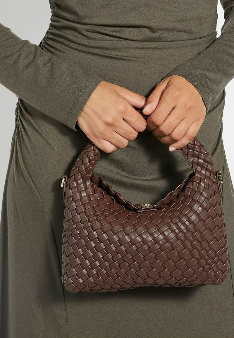 Sac à main tressé marron avec une prise ronde. Fabriqué en matériau texturé, il présente un design tressé marqué et des accents matériels subtils.