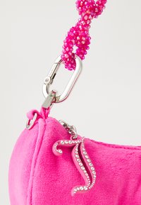 Borsa in velluto rosa brillante con una superficie testurizzata, dotata di un manico in perline rosa e un moschettone in argento. Caratteristico charm a forma di J con strass.