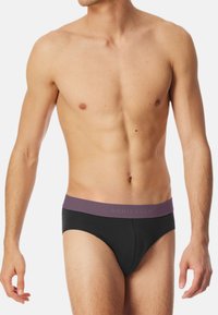 Zwarte boxershorts met een paarse tailleband waarop de merknamen staat. Glad materiaal, nauwsluitend ontwerp en lage taille.
