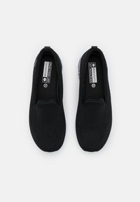 Black slip-on shoes with a soft mesh upper, textured design, and cushioned insoles. Features a round toe and a lightweight, flexible sole.