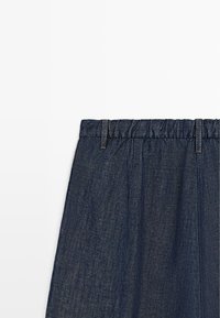 Dunkelblauer Jeansrock mit elastischem Bund und Gürtelschlaufen, von der Taille abwärts auf weißem Hintergrund gezeigt.