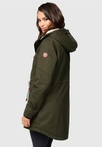 Olivengroene parka met een met bont gevoerde capuchon, rits en drukknopen, verstelbare koordjes en een leren logo patch op de mouw.