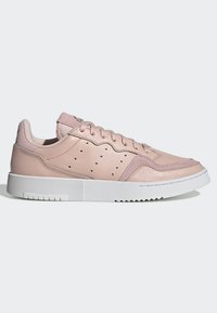 Zapatillas de cuero rosa claro con un acabado texturizado, detalles perforados, acentos en contraste y una suela de goma blanca. Incluye cordones planos.