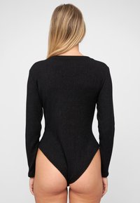 Schwarzer, gerippter Bodysuit mit langen Ärmeln, hoher Ausschnitt am Rücken und glatter Textur. Verfügt über einen runden Halsausschnitt und eine figurbetonte Passform.