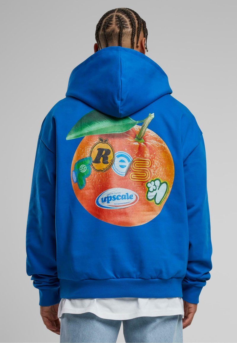 Sudadera de algodón azul con un gran gráfico naranja en la parte posterior que presenta varios logotipos coloridos y un detalle de hoja verde. Puños y dobladillo con canalé.
