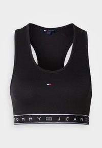 Μαύρο αθλητικό σουτιέν crop top από λείο ύφασμα. Διαθέτει σχέδιο racerback και λευκή ταινία με το λογότυπο «TOMMY JEANS». Μικρό λογότυπο στο μπροστινό μέρος.
