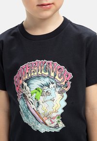 Camiseta de algodón negra con un diseño gráfico colorido de un esqueleto surfeando una ola, con la palabra "Quiksilver" en letras estilizadas y en negrita.
