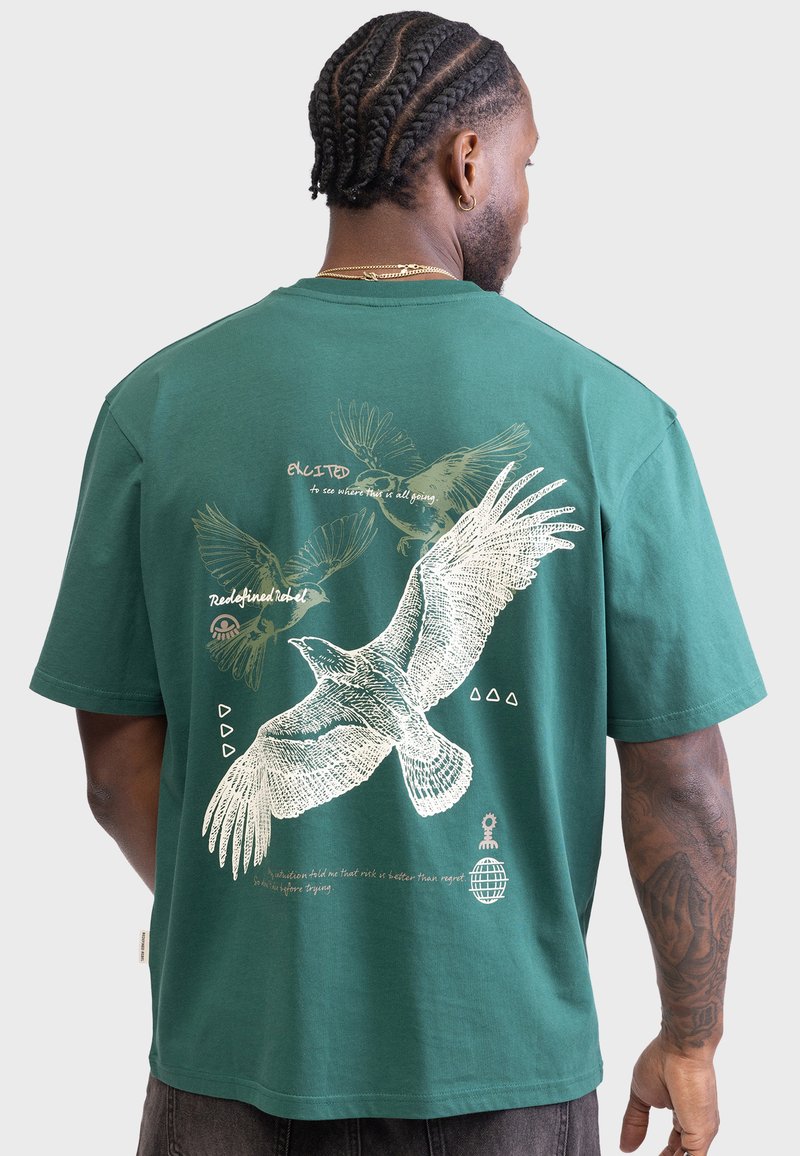 T-shirt en coton vert avec un motif artistique d'oiseaux et du texte au dos, à manches courtes et coupe décontractée.