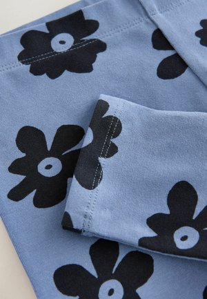 Helles blaues Material mit kräftigen schwarzen Blumenmustern und kreisförmigen Akzenten. Sanfte Textur und gesäumte Kanten. Zwei sichtbare Abschnitte.