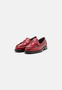 Mocassins de verniz vermelho com bico redondo, apresentando uma tira decorativa sobre o peito do pé e sola baixa e plana em borracha preta.