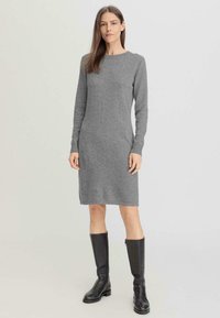Abito lavorato a maglia grigio a maniche lunghe con scollo rotondo, corpino attillato e silhouette dritta, abbinato a stivali alti fino al ginocchio in pelle nera.