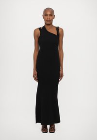 Black, form-fitting dress with a one-shoulder design, featuring decorative hardware on the strap. Floor-length with smooth, stretchy fabric.