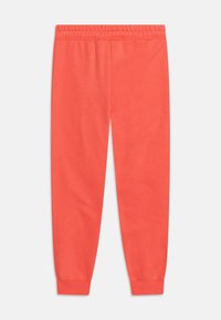 Coral jogger pants made from soft fabric with an elastic waistband and tapered cuffs, featuring a smooth texture with no visible patterns.