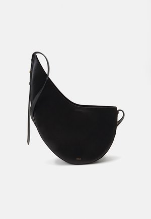 Black leather handbag with a curved moon shape, featuring a slim strap and subtle gold branding on the front. Smooth texture with minimal hardware.