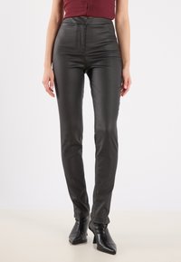 Black faux leather pants with a high waist, slim fit, and a smooth texture. Features a front zipper and stitched detailing along the legs.