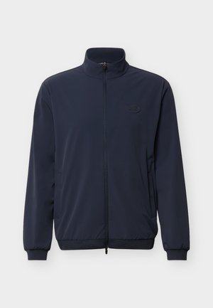 Μπουφάν σε σκούρο μπλε του ναυτικού με πλήρες φερμουάρ, ψηλό γιακά, πλαϊνές τσέπες, ριμπ μανσέτες και διακριτικό λογότυπο στην αριστερή περιοχή του στήθους.