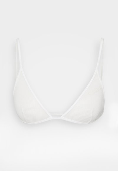 Hvit ribbestrikket stoff bralette med trekantede kopper, tynne justerbare skulderstropper og et minimalistisk design.