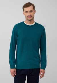 Türkis gestrickter Pullover mit rundem Halsausschnitt, gerippten Bündchen und Saum. Enthält ein kleines Logo auf der Brust und hat eine glatte Textur.