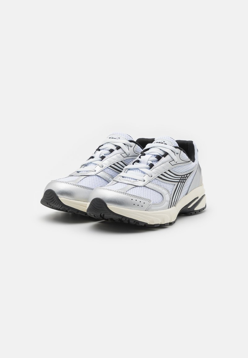 Sneaker leggere con una parte superiore in rete bianca e argento, accenti neri, suola in gomma spessa e dettagli di cucitura a contrasto.