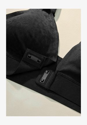 Černá podprsenka z texturované látky s jemným vzorem, vybavená nastavitelnými ramínky a černým zapínáním.