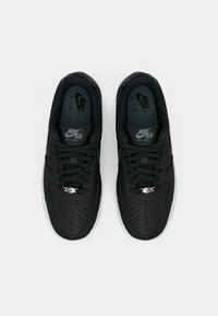 Crne Nike Air Force 1 tenisice s teksturiranim kožnim gornjištem, crnim vezicama i srebrnim detaljima. Imaju bijeli gumeni potplat i logotip na jeziku.