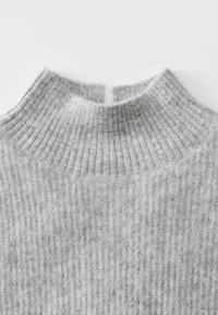 Helles graues geripptes Strickoberteil mit einem kleinen Schlitz in der Mitte, der eine weiche und flauschige Textur zeigt.