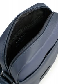 Borsa in tessuto texturizzato blu navy con apertura con zip, dotata di un interno scuro e di una tasca interna con zip aggiuntiva.
