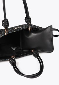Černá tkaná kabelka s dekorativním vícebarevným prošíváním. Obsahuje odnímatelnou černou koženou tašku a hladké kožené uchy s uzlovými akcenty.