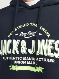 Sudadera navy con el logotipo "Jack & Jones", texto en blanco y verde, cordón en la capucha y detalles de banner "Establecido en 1990" en la parte frontal.