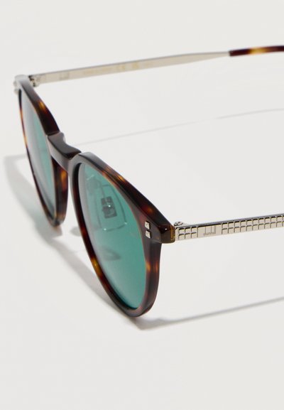 Στρογγυλά γυαλιά ηλίου με καβούκι χελώνας, πράσινους φακούς και χρυσά μεταλλικά μπράτσα με σχεδιασμό πλέγματος και ανάγλυφη την επιγραφή "dunhill".