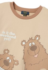 Camiseta de algodón beige con detalles marrones, que presenta osos de dibujos animados y el texto "¿Ya es fin de semana?" Escote redondo y mangas cortas.