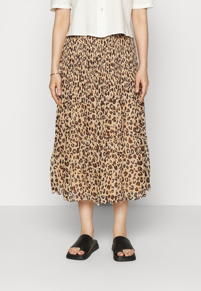 Falda midi plizada en beige con un estampado de leopardo. Combinada con sandalias negras tipo slide. La tela tiene una textura suave y fluida.