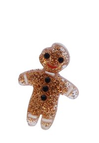 Adorno en forma de hombre de jengibre hecho de un material transparente lleno de purpurina dorada, con ojos de cuentas negras y una sonrisa roja.