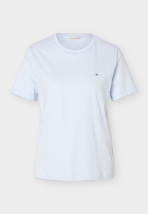 Camiseta lisa de color azul claro, de manga corta y cuello redondo, con un pequeño logo de escudo en el pecho izquierdo.