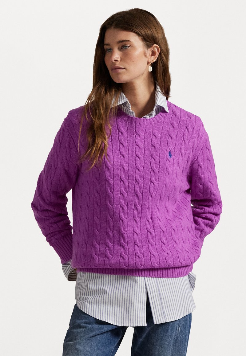 Paarse kabelgebreide trui met geribbelde zoom en manchetten, laag over een blauw-wit gestreepte button-up shirt. Casual ontwerp.