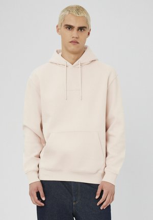 Hoodie rose clair en tissu doux avec une poche frontale et une capuche à cordon de serrage. Doté d'un logo brodé minimaliste sur la poitrine.