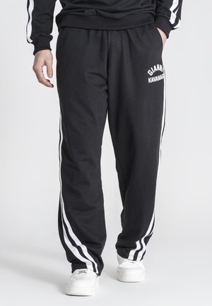 Black sweatpants featuring white side stripes, elastic waistband, and logo detail on the left thigh. Made from soft, comfortable material.